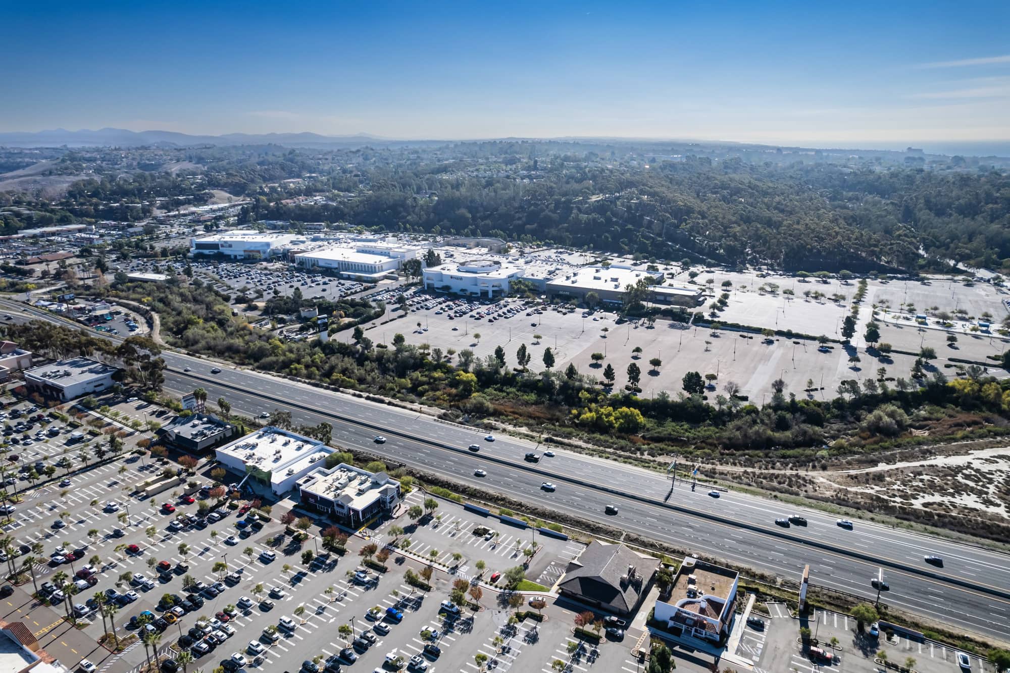 Aerial view of a retail corridor of shopping centers and parking fields