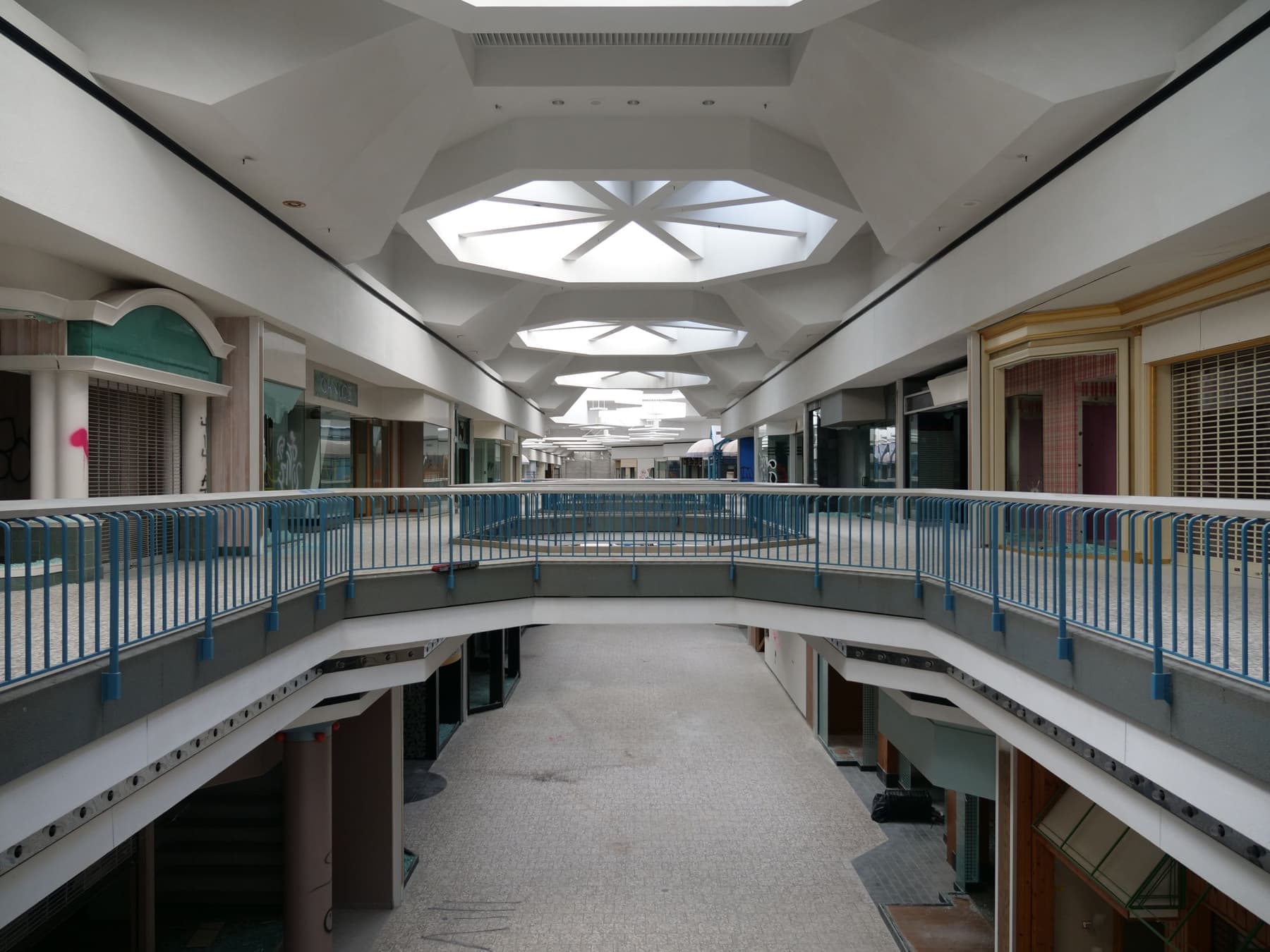 An enclosed shopping center concourse with storefronts closed